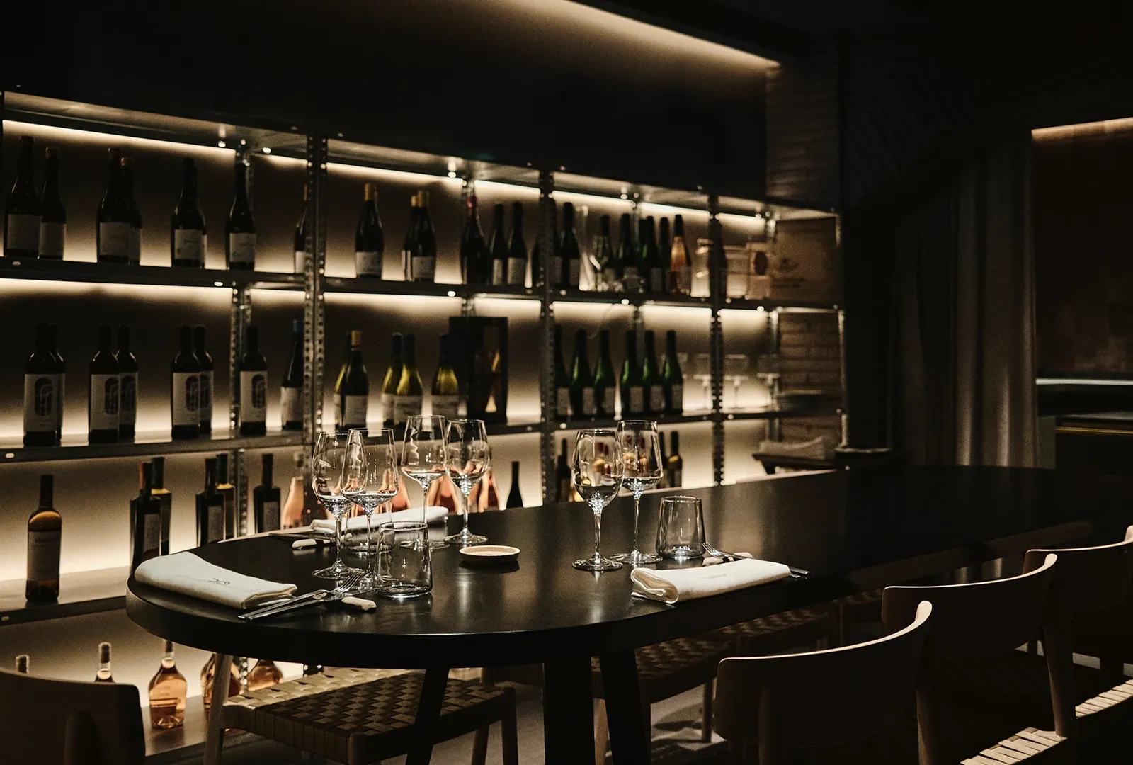 Mesa de la barra con la bodega iluminada detrás